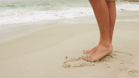 sección baja del hombre jugando con arena en la playa 4k