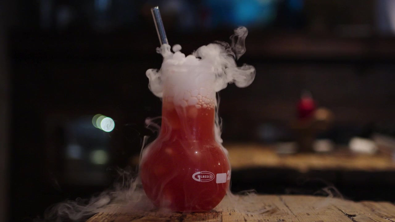 Primo piano al rallentatore di cocktail rosso con fumo di ghiaccio secco in bicchiere da laboratorio in un bar a Praga, Repubblica Ceca