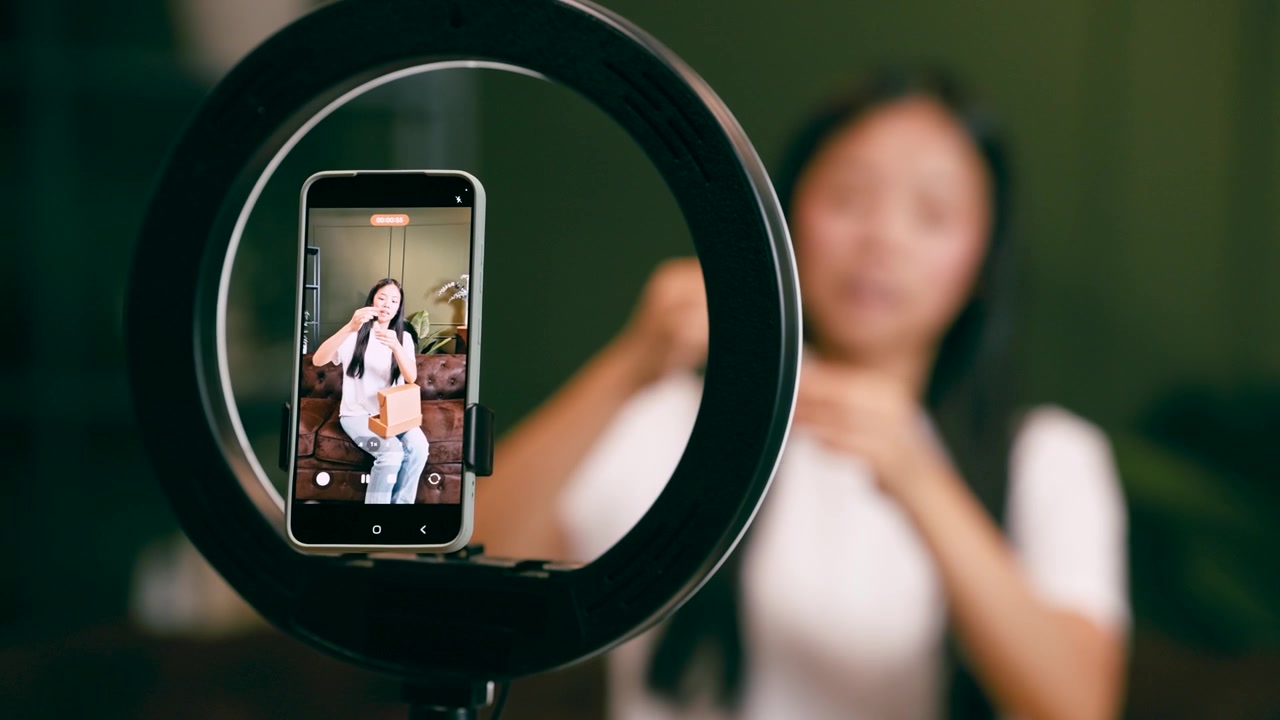 Young Woman Recording Video Content for Social Media Using Smartphone and Ring Light