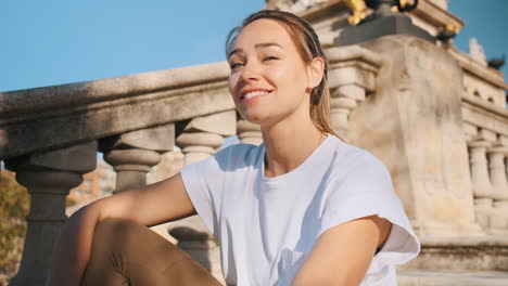 beautiful woman sitting on stairs in city park.