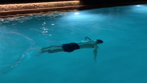 Man-leisurely-swimming-underwater-at-night