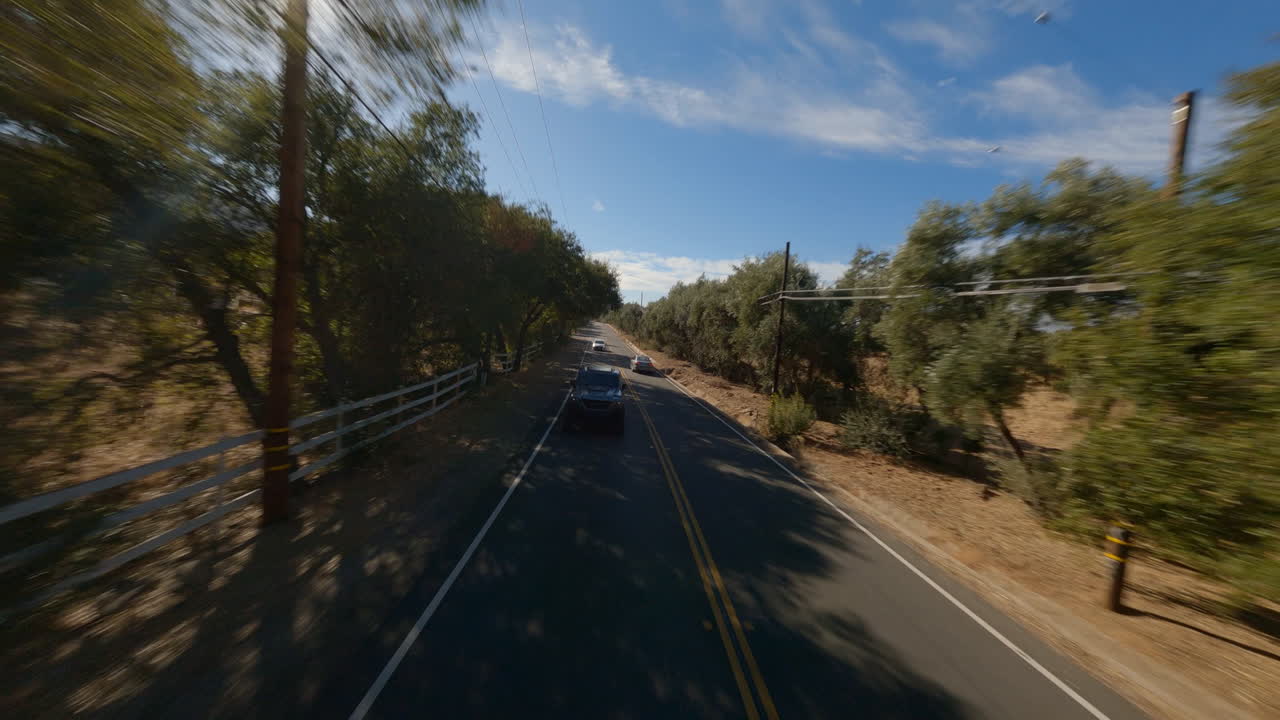 Ripresa drone FPV all'indietro di un'auto della polizia che guida attraverso la campagna.