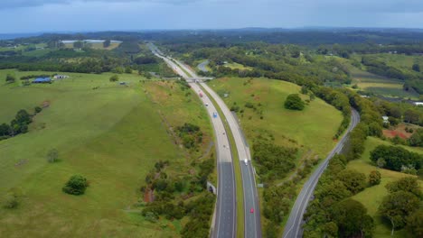 cars driving and travelling at pacific motorway carriageway by green hills and fields in byron bay, australia