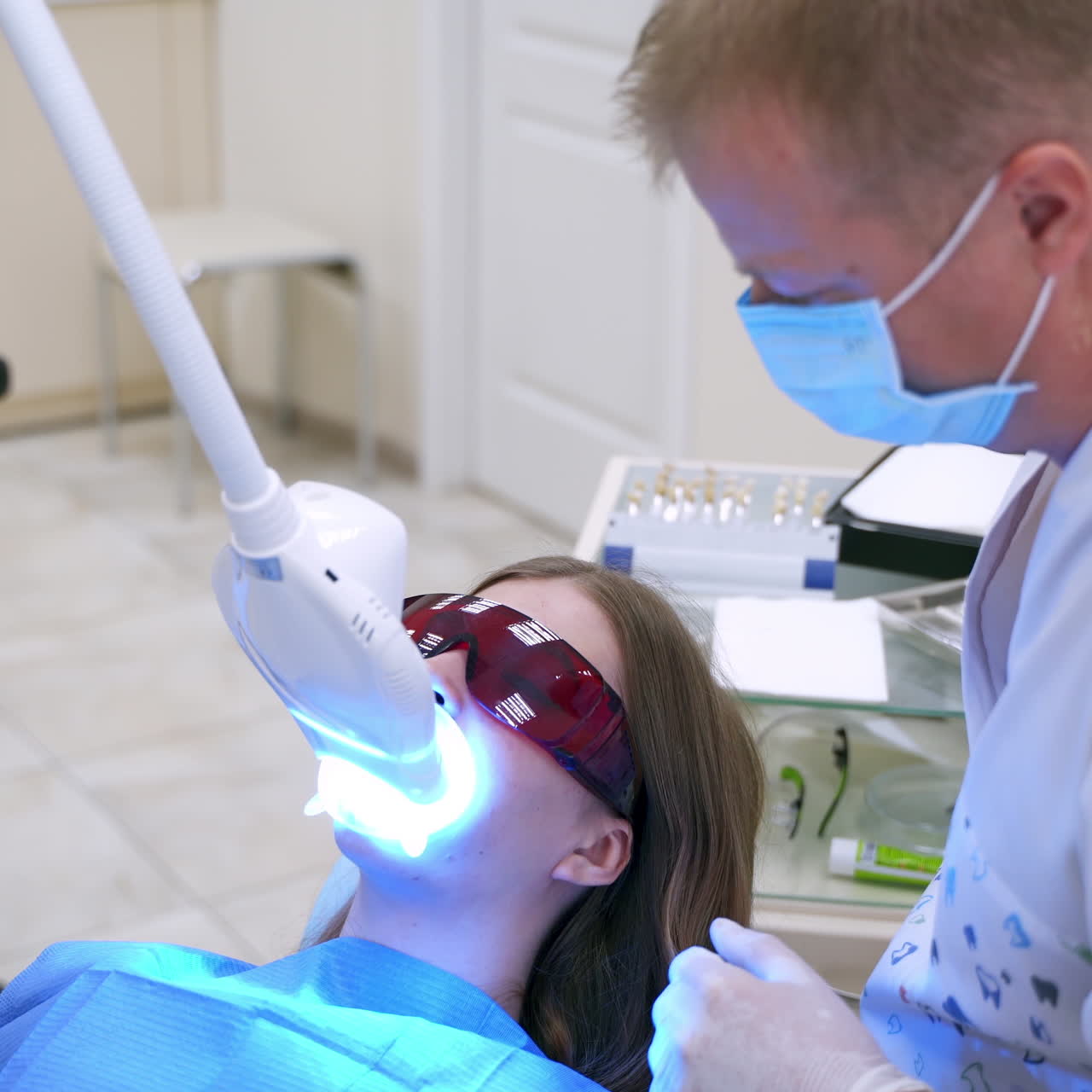 Modern equipment at dental clinic. Female patient lying in medical chair in special glasses at dentistry center. Dentist treating patient with new technology.