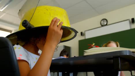 schoolgirl wearing firefighter helmet in classroom at school 4k