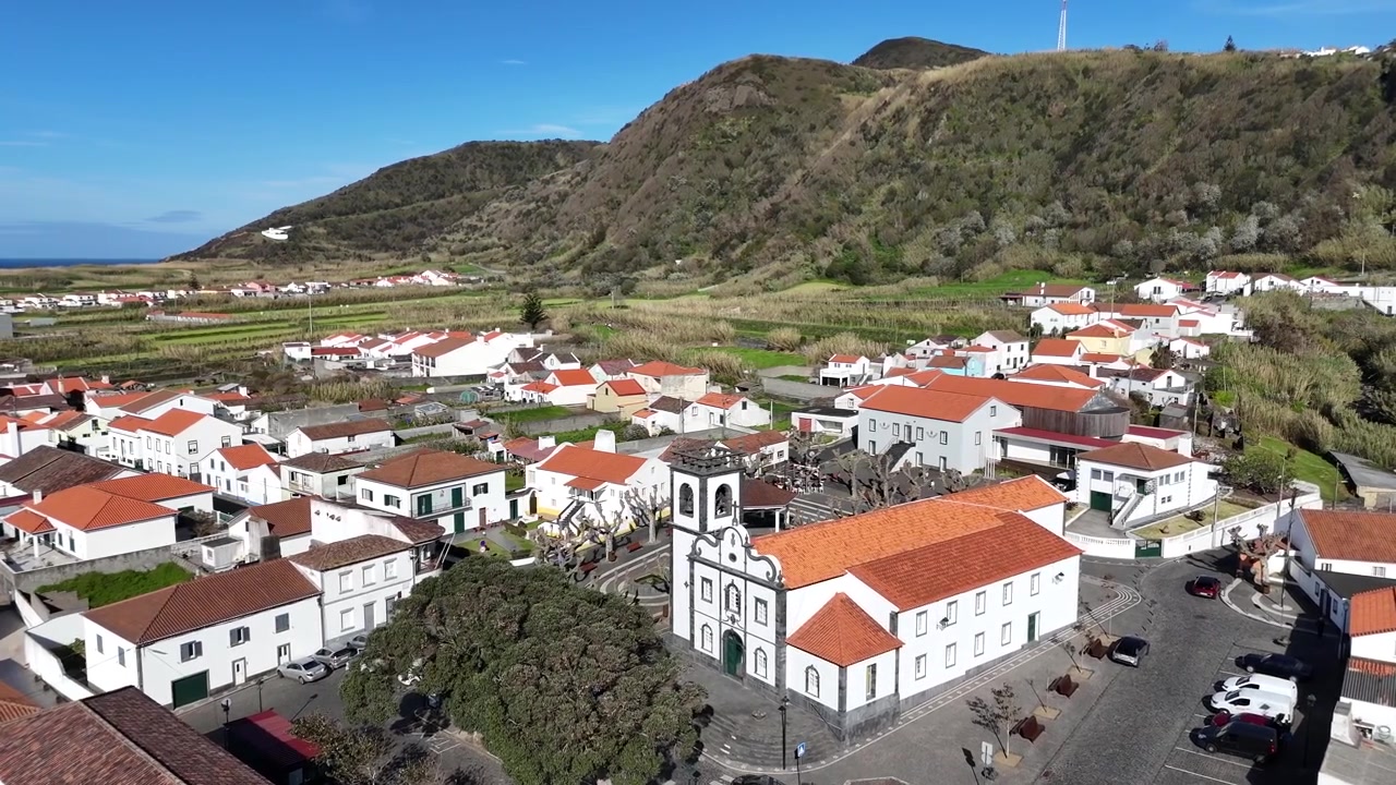 Mosteiros landsby droneflyvning over hvid kirke og traditionel arkitektur, der møder de mørke basaltklipper på Sao Miguel Island, Azorerne