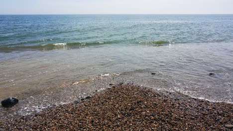 las olas golpean la orilla de la playa de guijarros en branscombe en la costa del canal inglés