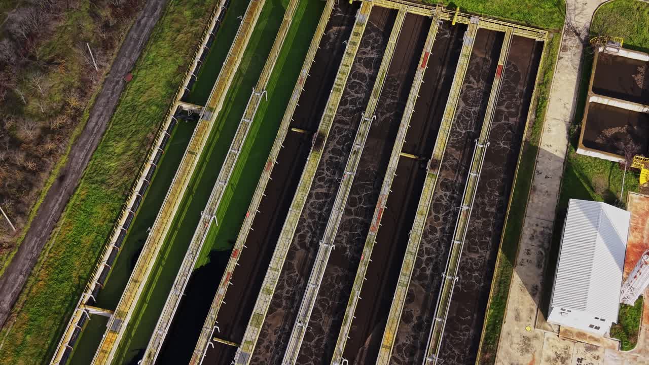 Overview of a wastewater treatment facility with open tanks and land