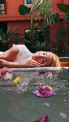 mujer relajándose en una piscina de jardín con flores