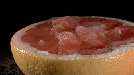 grapefruit with sugar in its own juice close-up. black background.