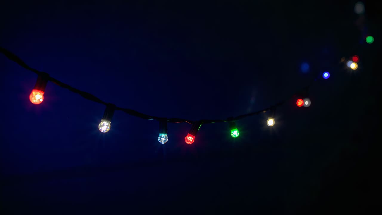 Sequence opening faceted LED string pulsing on black cable on dim wall, shifting color, making wash