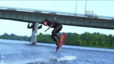 athlete wakeboarder jumping high above water. extreme stunt over water