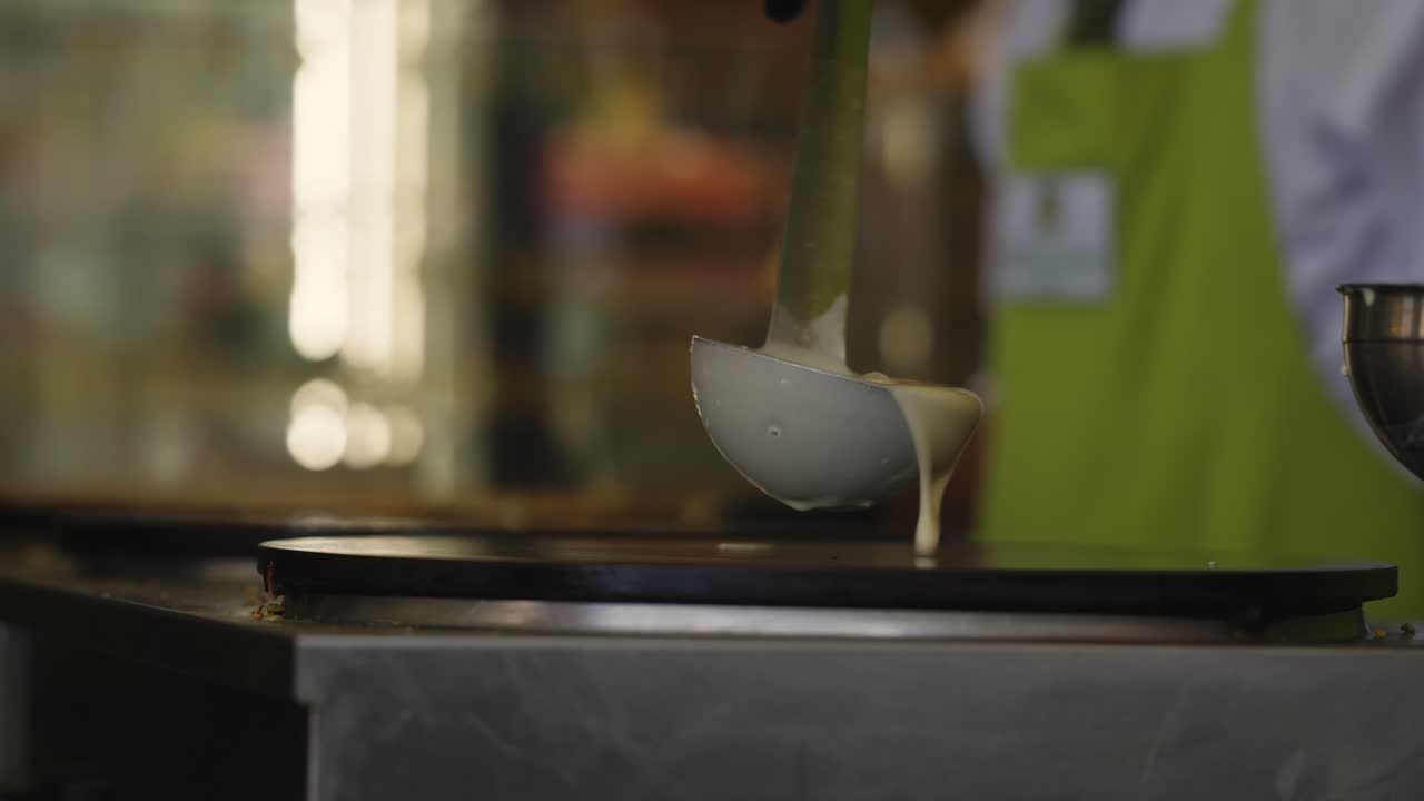Close up view in slow motion of A Chef pouring batter to prepare a crepe in a restaurant in Paris