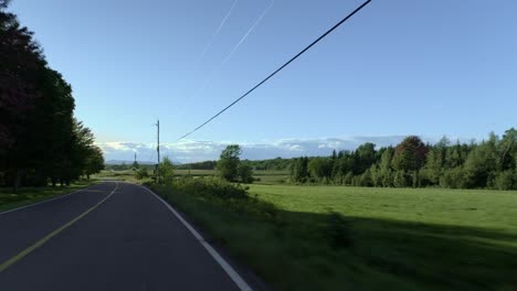 car driving on a calm and empty rural road on a sunny day