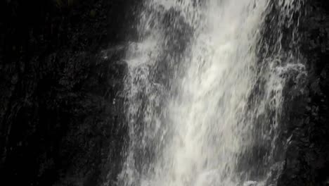un primer plano de una cascada que desemboca en una piscina seguida de una lenta inclinación hacia arriba