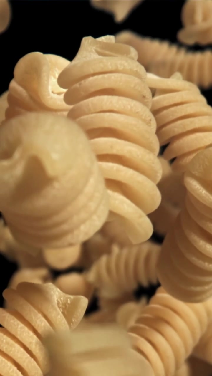 Fusilli secchi che cadono al rallentatore su sfondo nero
