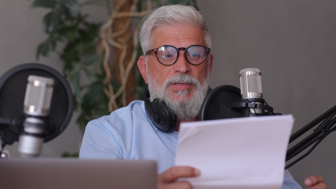 man records a podcast or interview with a microphone in a recording studio. senior sound engineer or radio host. an adult gray-haired man creates audio content