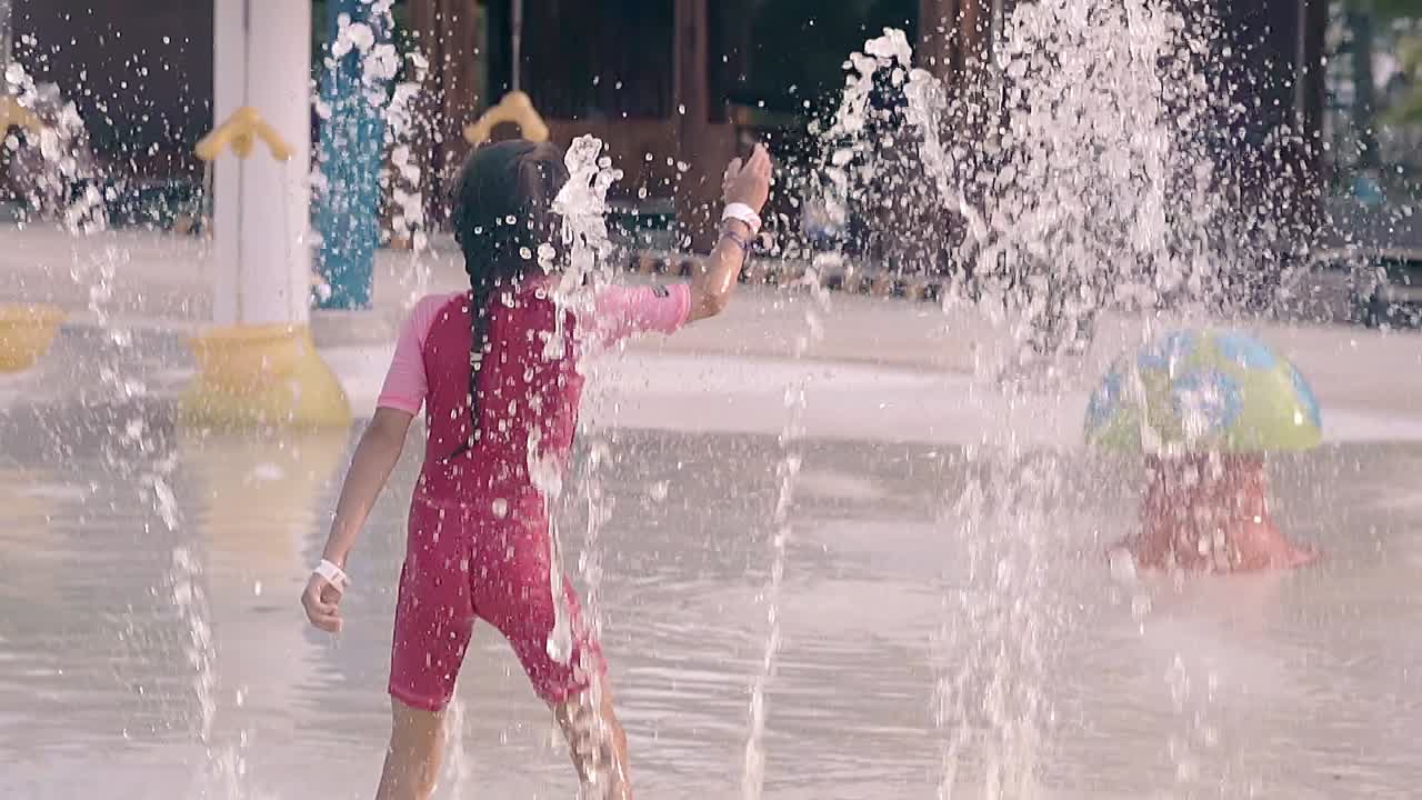 un niño lindo juega en el patio de recreo con fuentes en cámara lenta