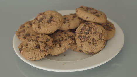 hand taking chocolate chip cookies from a white plate - high angle