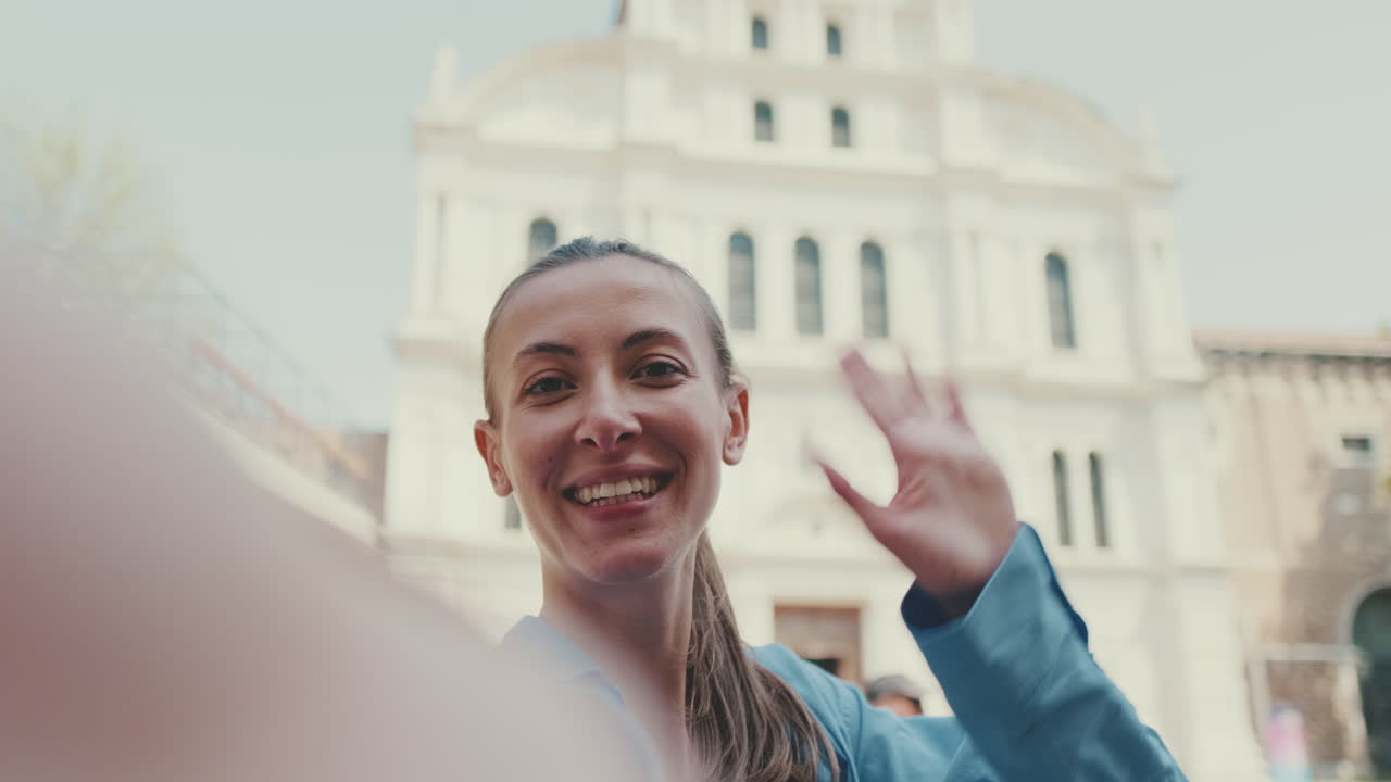 Happy Young Woman Waving and Gesturing in Front of Historic Building