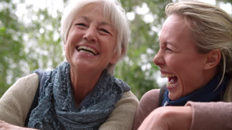 mother and adult daughter laughing outdoors, slow motion
