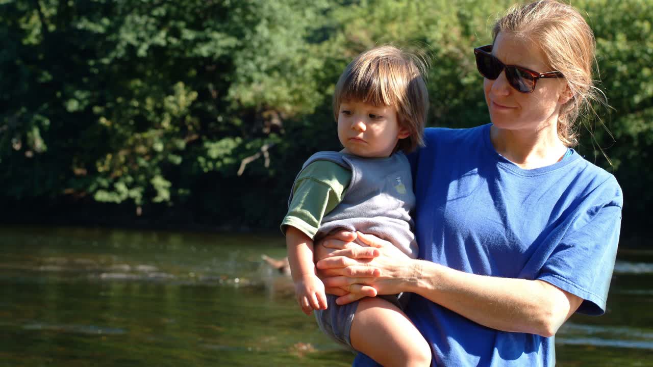 Woman holding a child by a river