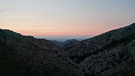 sunset between cliffs of a mountain landscape with the sea in the distant background