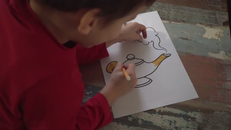 niño caucásico pintando una lámpara mágica dibujando con un marcador amarillo en el interior