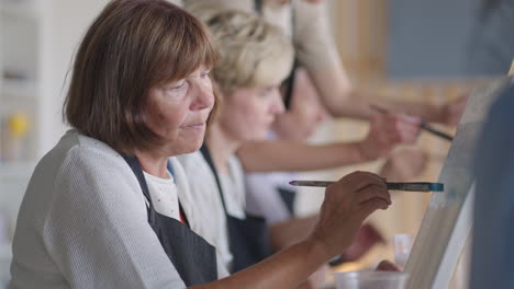 like senior friends attending together at a painting class. small group taking a variety of fun classes together. a group of elderly people attend a master class on drawing together spending time.