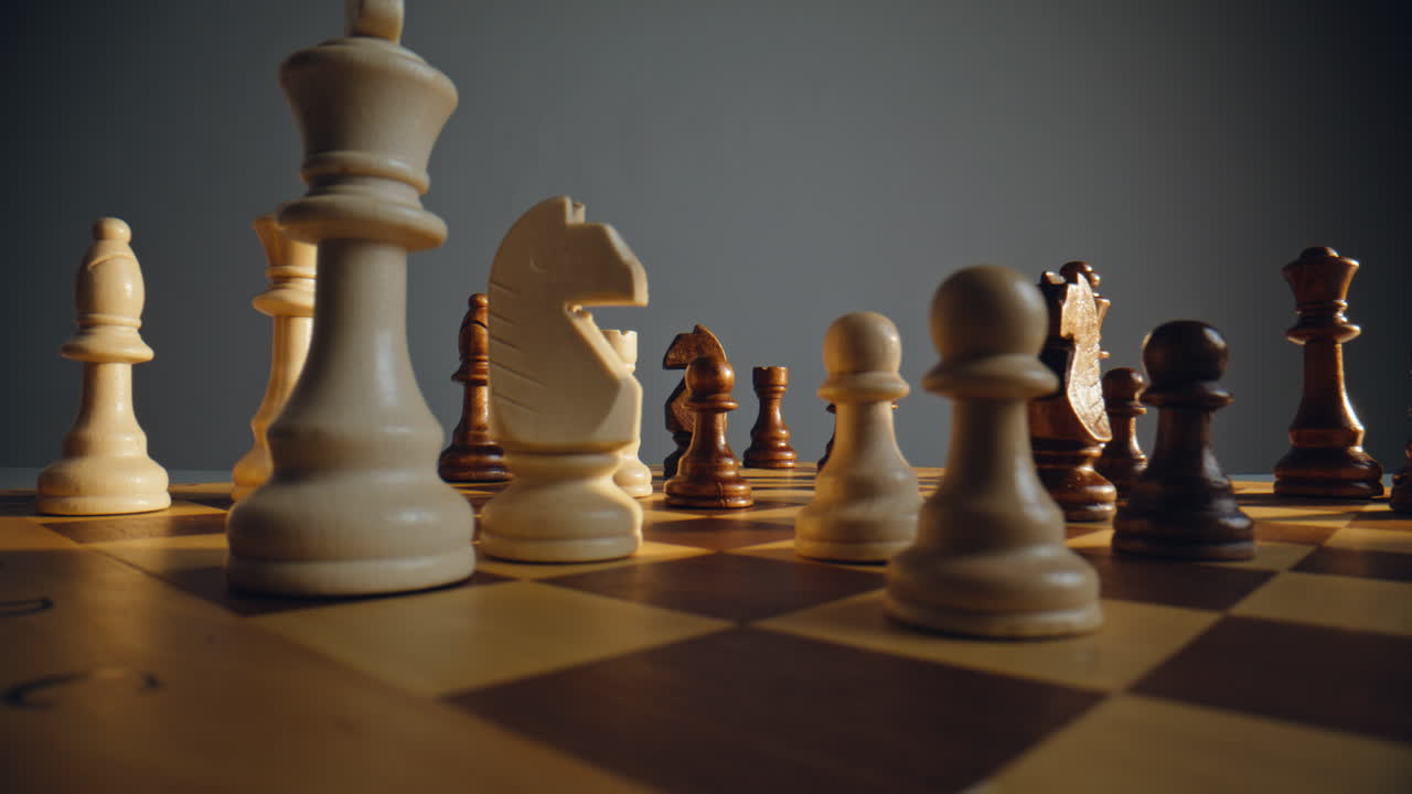 Hand directing ivory chess across grid with rival troops closeup. Strategic game