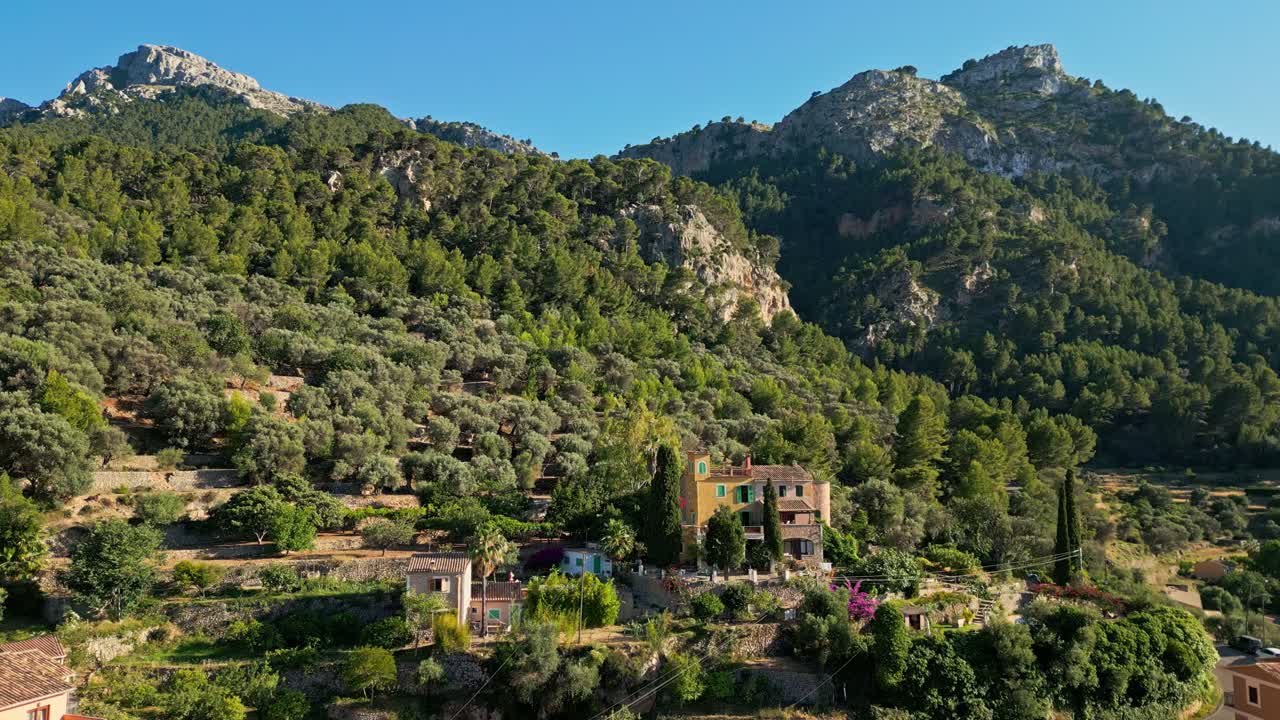 A classic Mediterranean-style house sits elegantly above the village of Estellencs in Mallorca, surrounded by the scenic beauty of the Serra de Tramuntana mountains.