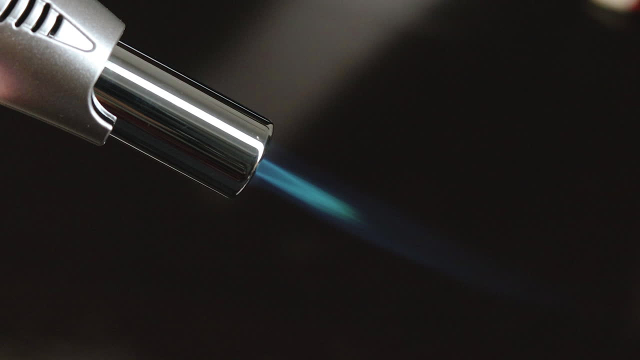 vista lateral de primer plano en la punta de metal del soplete que se utiliza en la luz de llama azul oscura