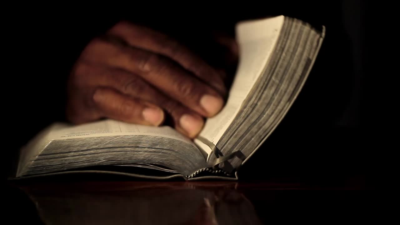 Praying to God with hand on bible black background with people stock footage-1