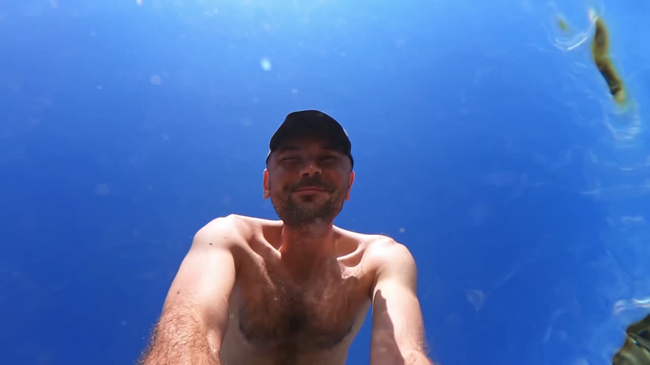 Man shooting himself under the water of the Aegean sea. Slow motion, underwater shooting. Greece