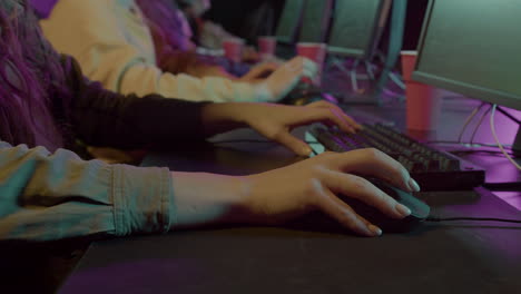 close up of a female gamer's hand on a computer mouse playing virtual video games while sitting with her team in gaming club 1