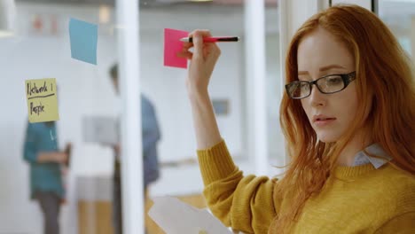 mujer ejecutiva escribiendo en notas adhesivas en la oficina 4k