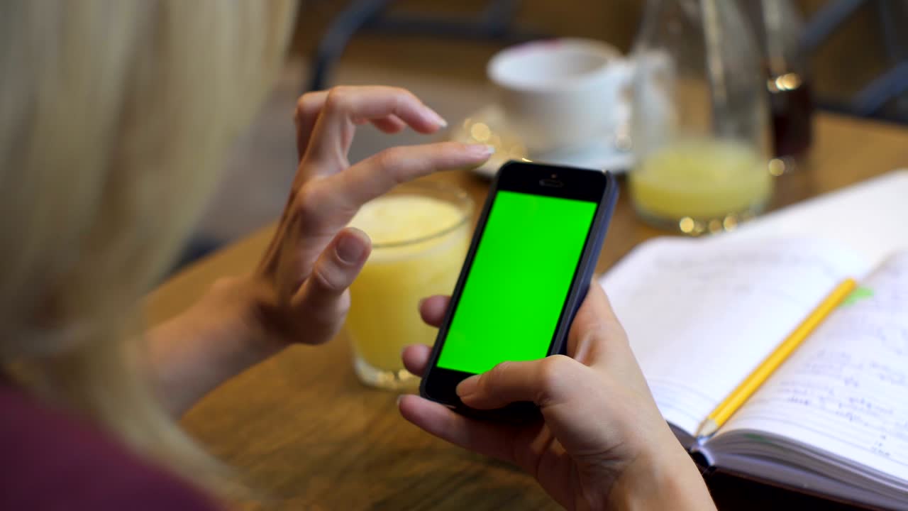 mujer de negocios usando un teléfono inteligente en una cafetería. teléfono inteligente con pantalla verde