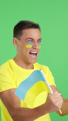 ukrainian supporter screaming and waving a national flag looking away
