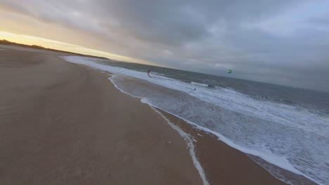 sigue la toma de un dron de un kitesurfer al atardecer