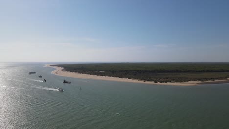 drone footage of bonanza beach, at the mouth of the guadalquivir river. there are small fishing boats on the shore and in the background you can see the doñana natural park.