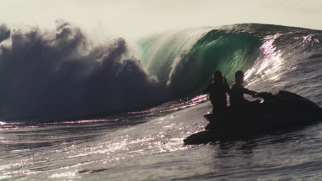 Jet-ski-watches-as-huge-ocean-wave-barrels-from-over-side-of-shoulder-at-sunset