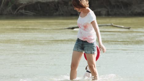 woman playing with dog near river