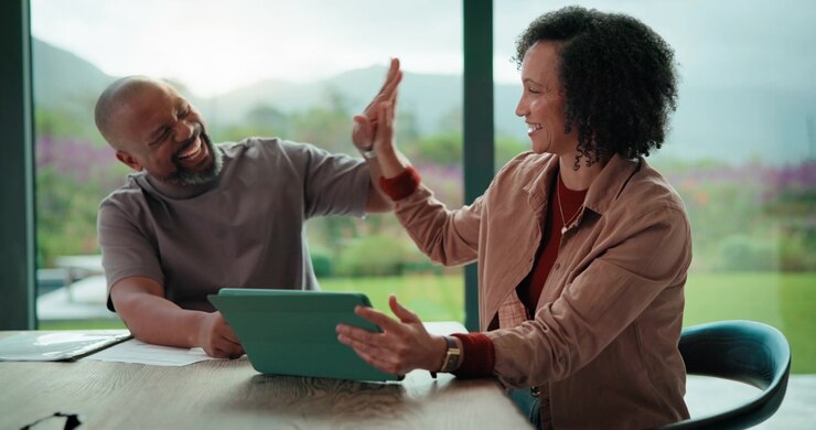 Happy Couple Celebrating Success While Using Tablet at Home
