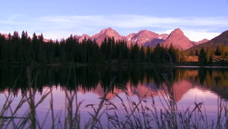 the rocky mountains are perfectly reflected in an alpine lake at sunset or dawn in this traveing shot 1