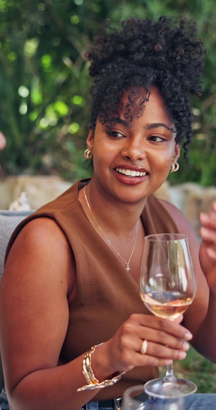 Young Woman Enjoying Wine and Conversation Outdoors