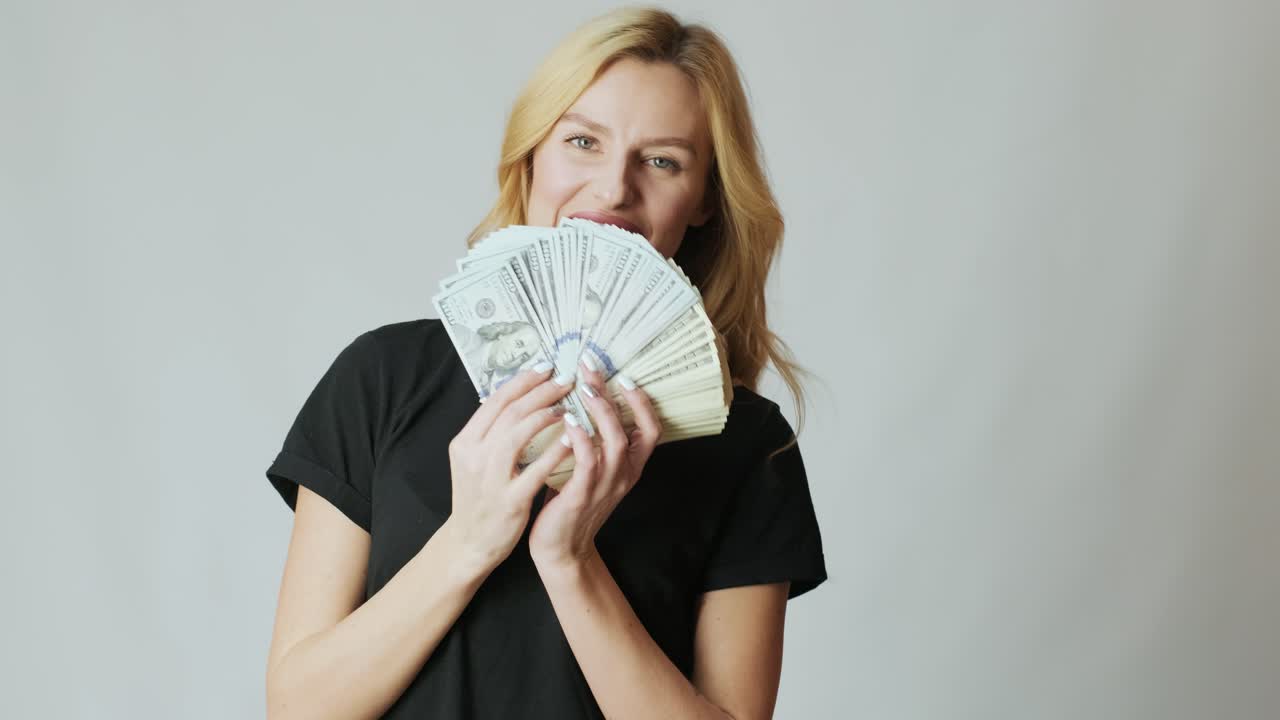 Mooi meisje met veel dollars in de handen op een witte achtergrond.
