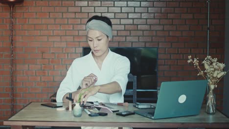woman applying makeup while working from home