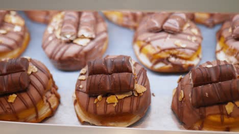 donuts with chocolate bars on top displayed in showcase