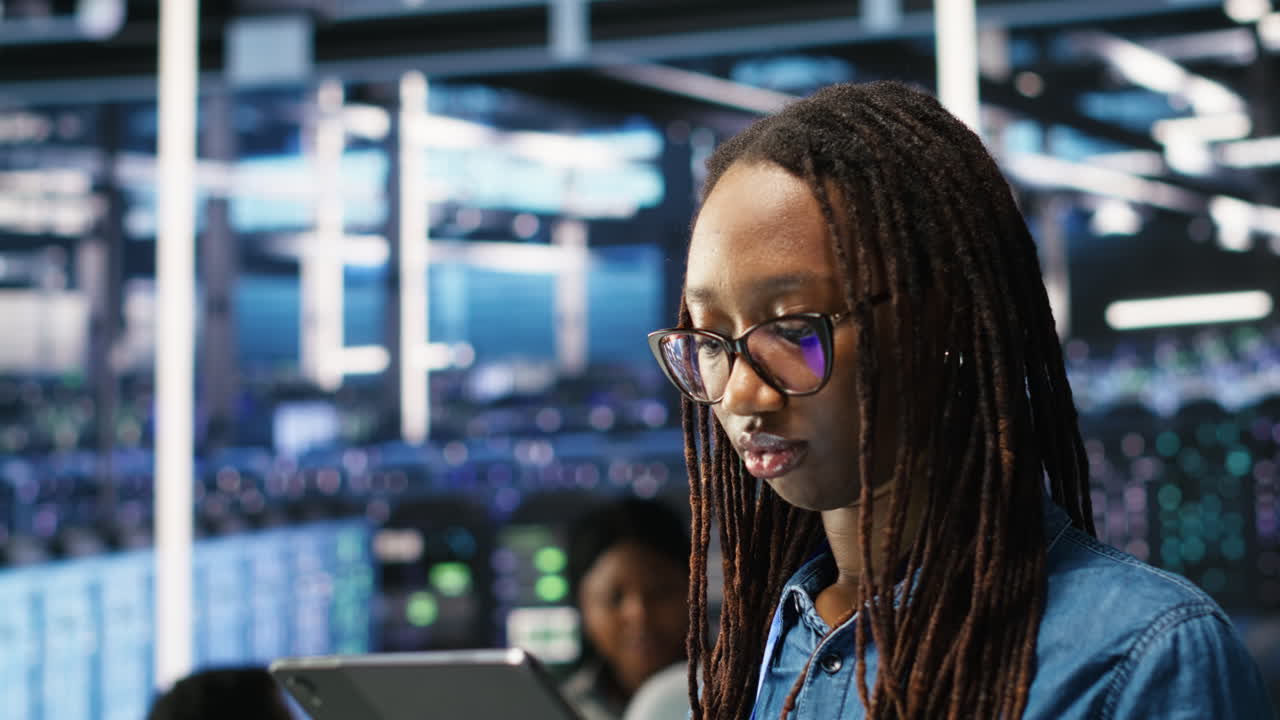 Portrait of smiling server room engineer using device to interpret AI data