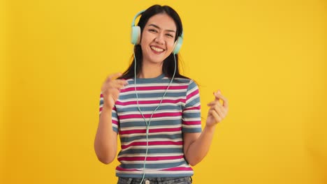 happy attractive asian young woman dancing isolated on yellow background.cheerful pretty girl happy with tablet notebook online music smiling and moving body follow music with positive.